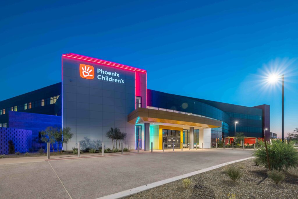 Exterior view of Phoenix Children's hospital building illuminated with colorful lights at dusk.